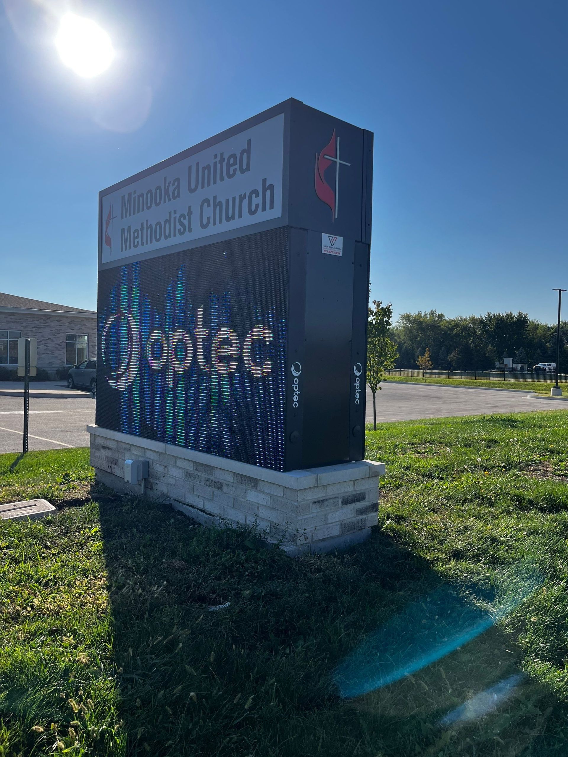 Digital sign for a United Methodist church in a sunny grassy lot with lens flare