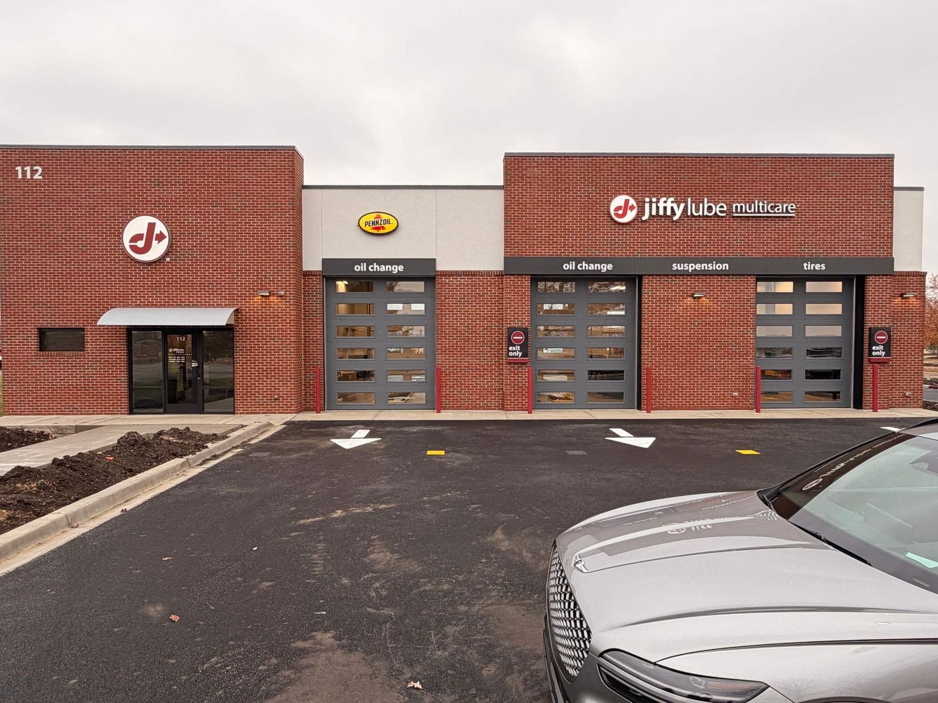 Jiffy Lube storefront with brick facade and parking lot, front view of service bays