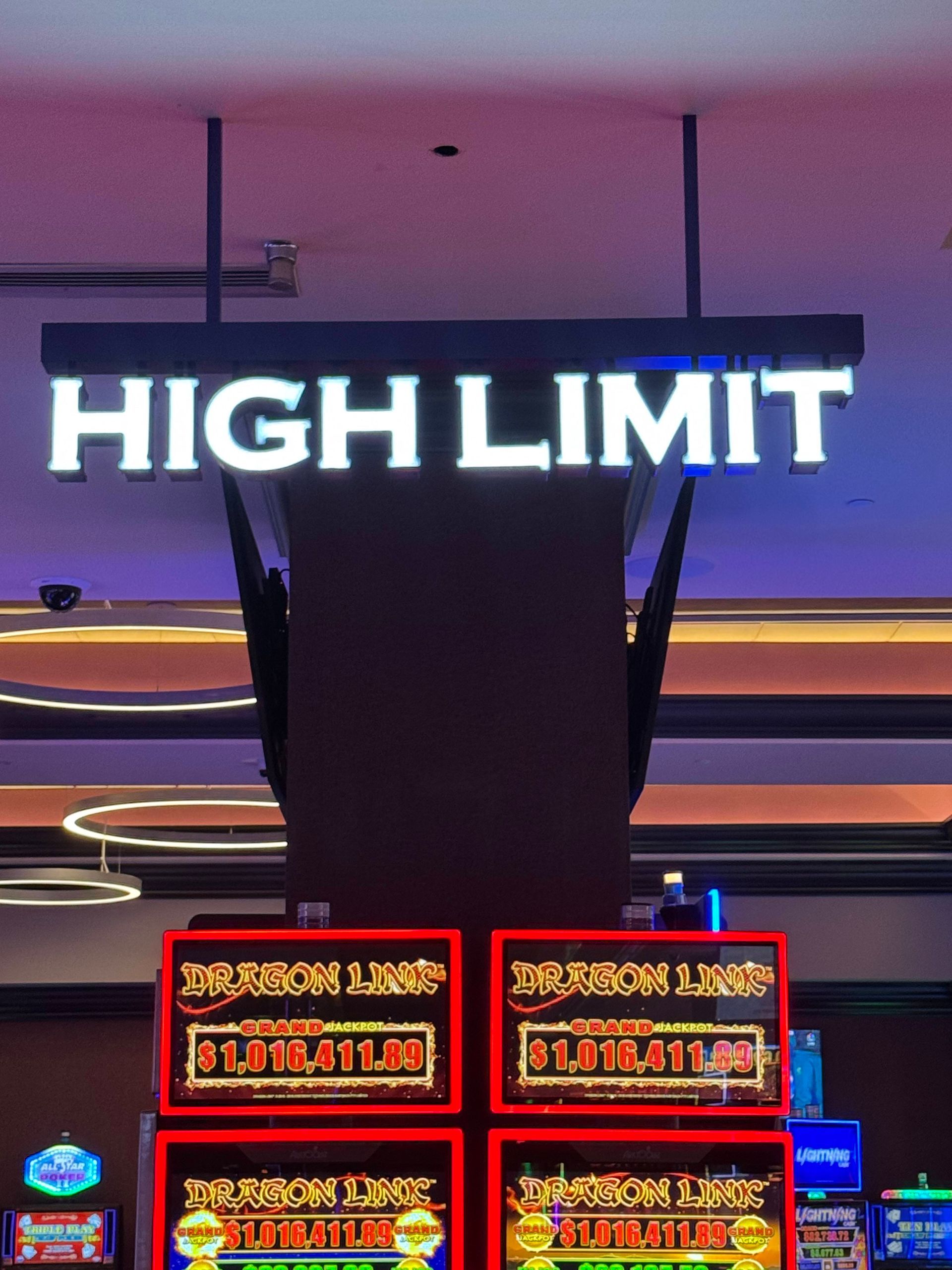 Illuminated “HIGH LIMIT” casino sign above red gaming machine displays at night