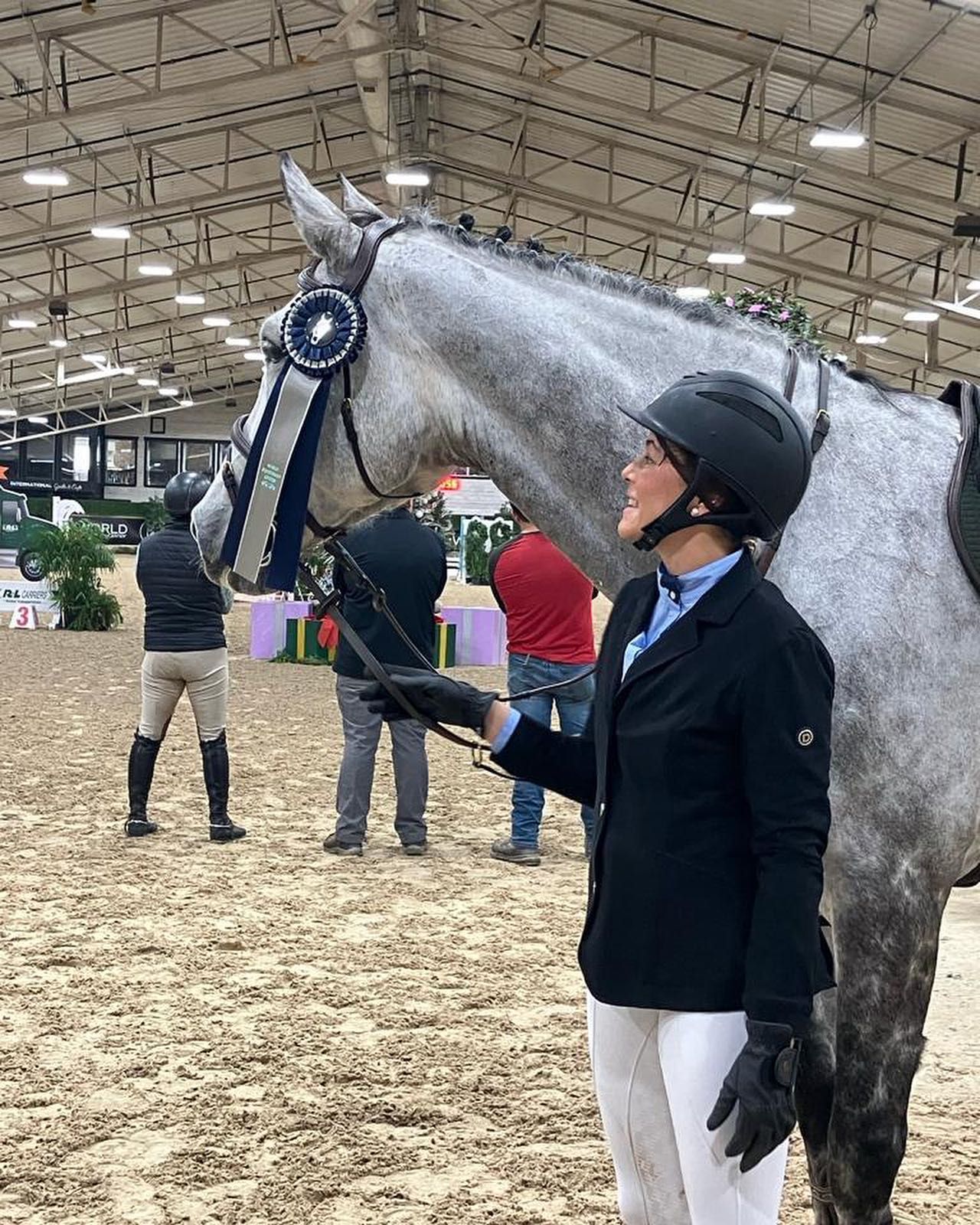 A woman is standing next to a gray horse.
