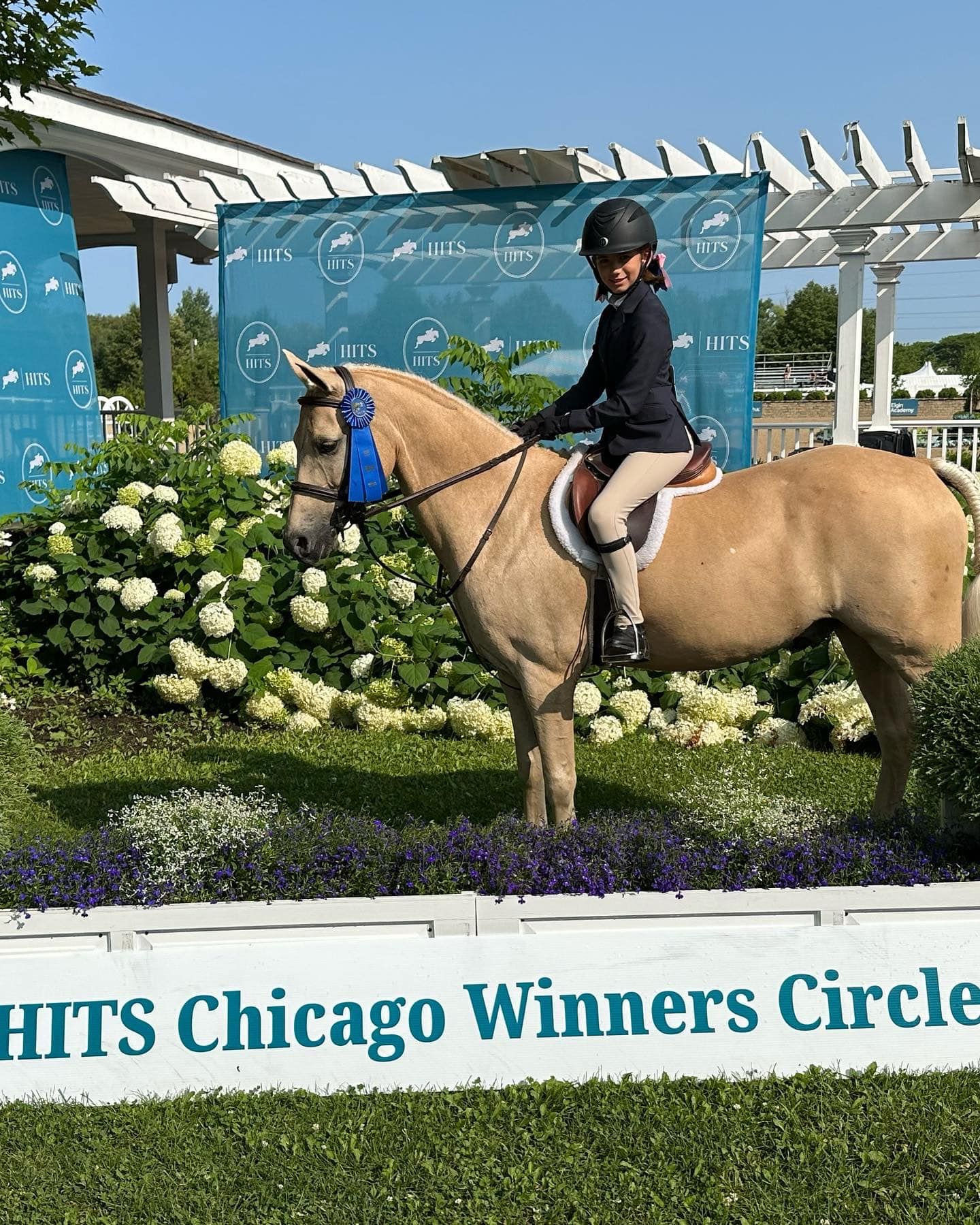 A woman is riding a horse in front of a sign that says hits chicago winners circle.