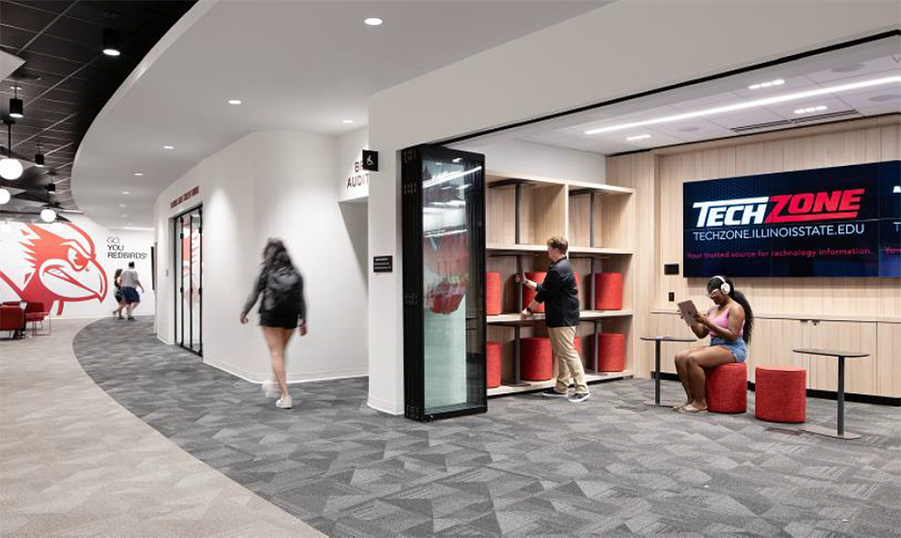 A group of people are walking down a hallway in a tech zone.