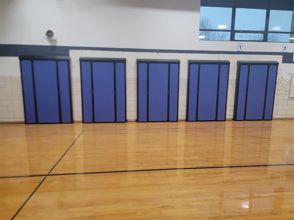 A gym with a wooden floor and purple walls.