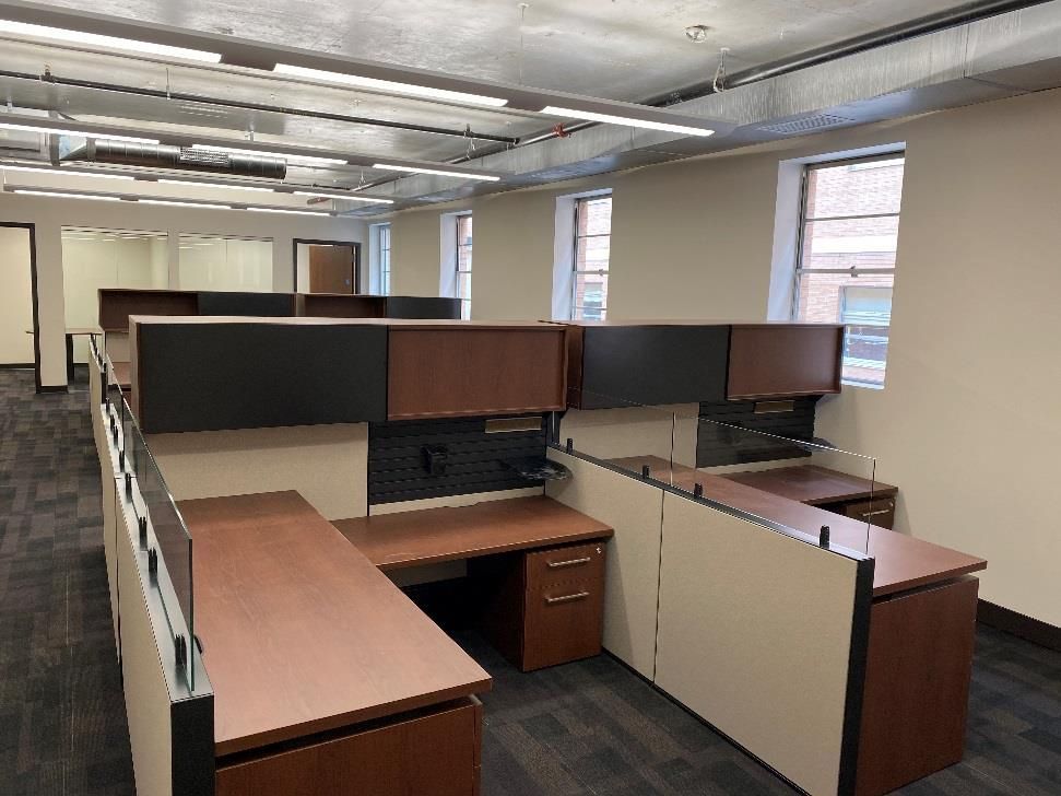 A large office with cubicles and a lot of windows