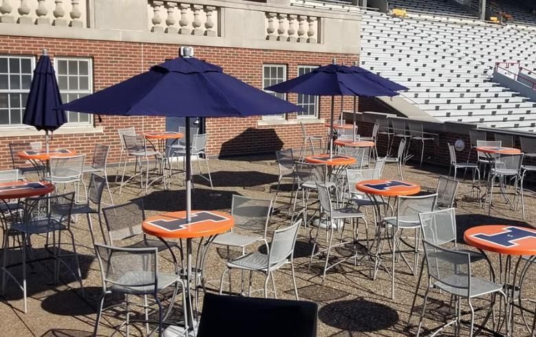 A patio with tables and chairs and umbrellas in front of a brick building