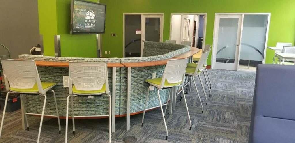 A room with a couch, chairs, tables and a television on the wall