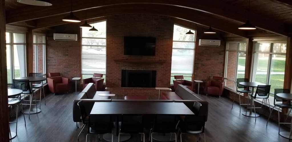 A large room with tables and chairs and a fireplace