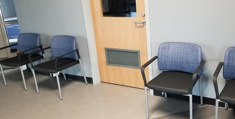 A row of chairs in a waiting room next to a door