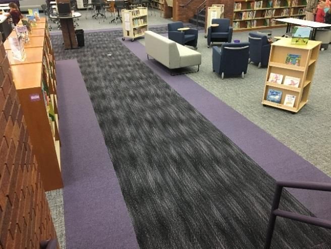 A library with a purple carpet and a couch and chairs