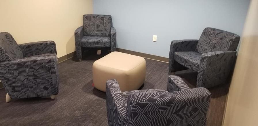 A room with four chairs and an ottoman in it