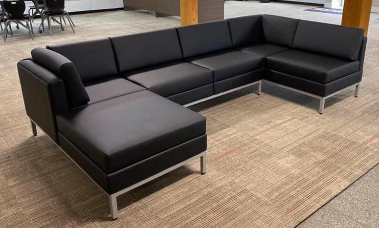 A large black sectional couch is sitting on a rug in a room