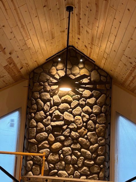 A stone wall with a ceiling fan hanging from it