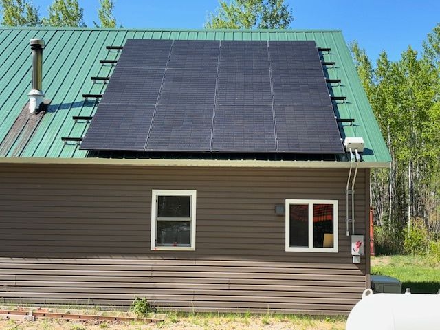 A house with a green roof and solar panels on it.