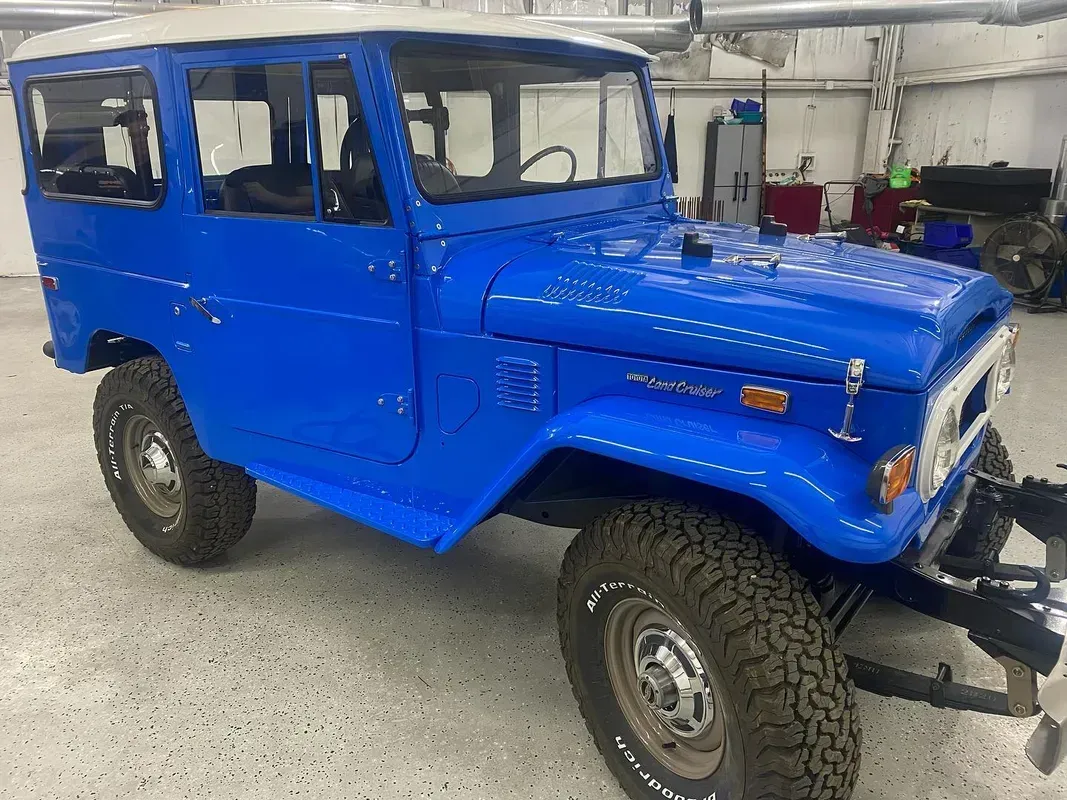 Blue Toyota FJ40 Land Cruiser SUV with a white roof in an indoor setting.