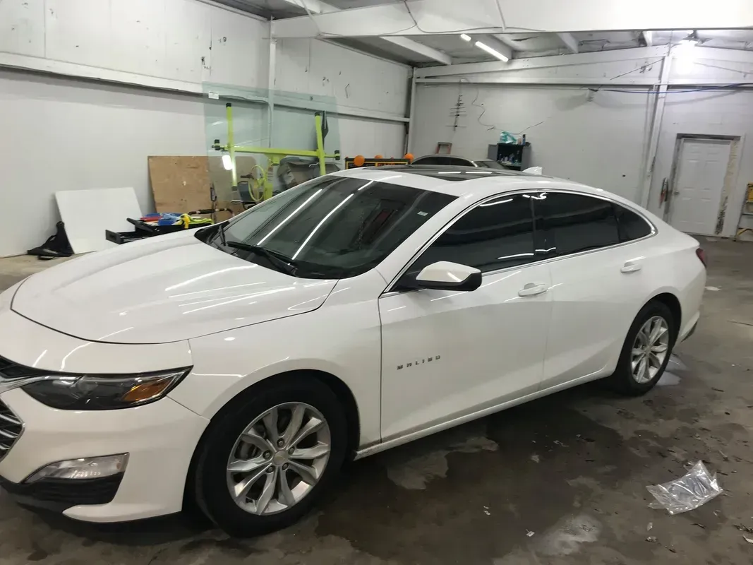White sedan with tinted windows in a garage.