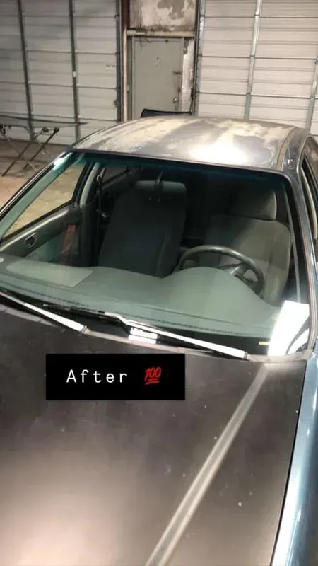 Gray car interior after repairs, windshield intact. Steering wheel, headrests visible.