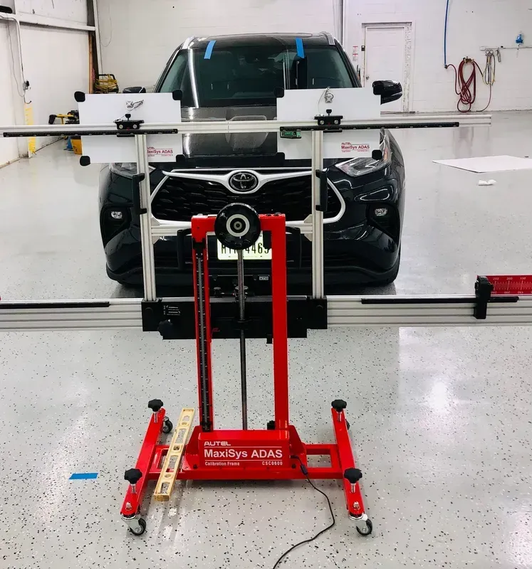 Red Maxisys ADAS machine calibrating a black Toyota SUV in a garage.