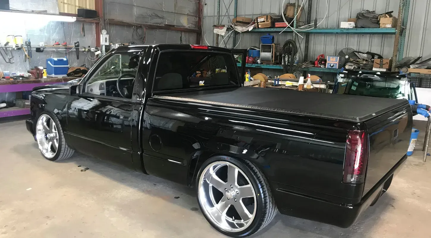 Black pickup truck with chrome rims in a garage.