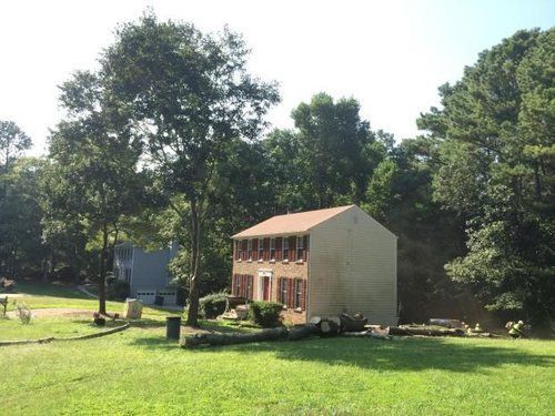 A small house sits in the middle of a lush green field