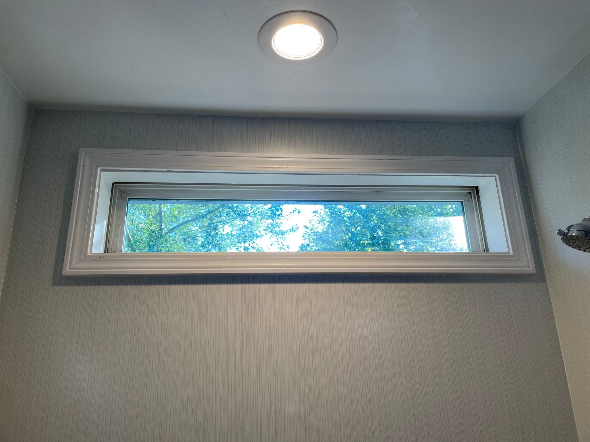 A bathroom with a window and a light on the ceiling