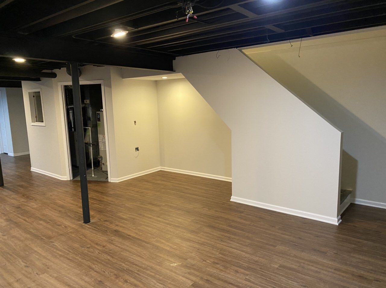 An empty basement with wooden floors and white walls