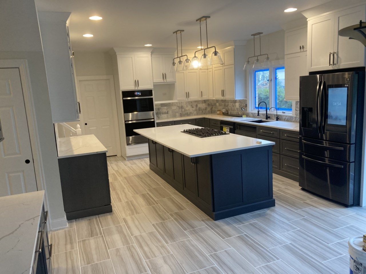 A kitchen with white cabinets, black appliances, and a large island