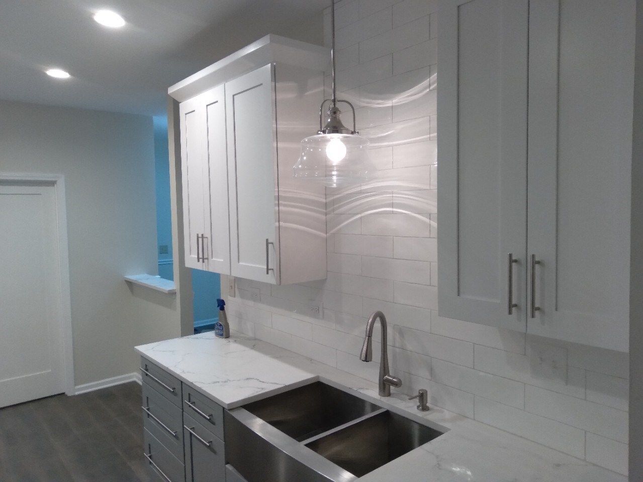 A kitchen with white cabinets and a stainless steel sink
