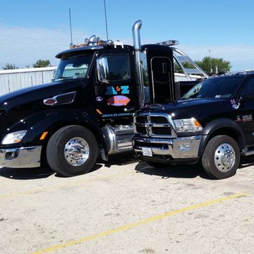 Two black trucks are parked next to each other with az on the side