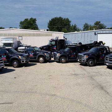 A row of black trucks are parked in a parking lot