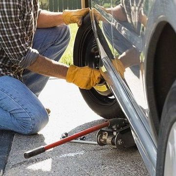 A man is changing a tire on a car with a jack