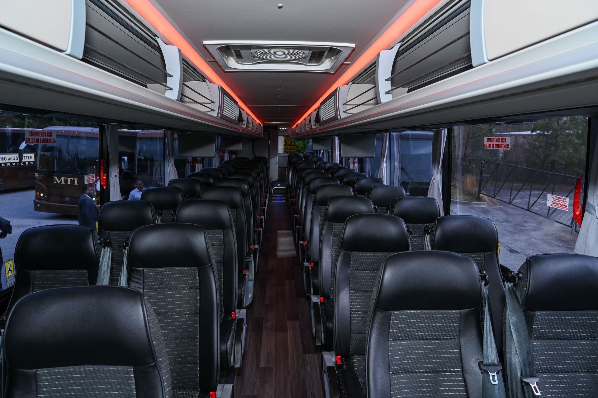Empty modern bus interior with rows of black seats and red ceiling lights