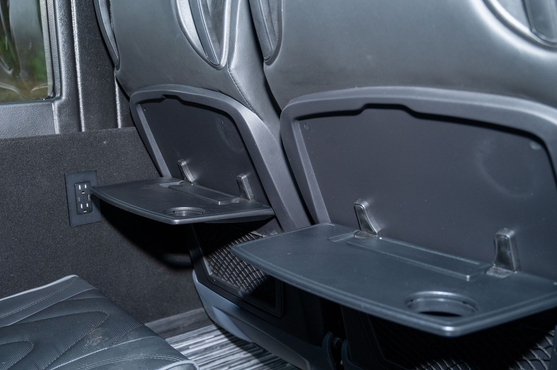 Rear seats of a car with folded-down armrests and cup holders, viewed from the back seat
