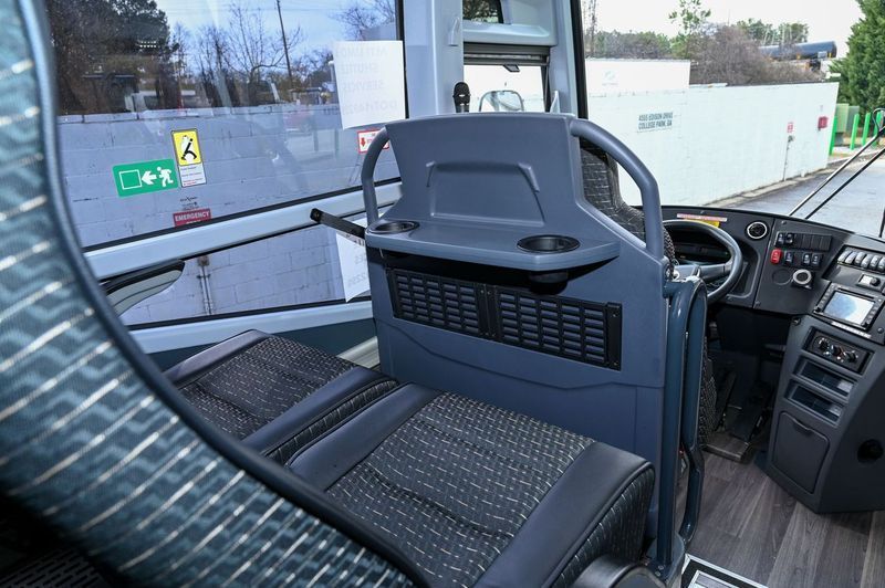 Empty bus interior with blue seats, front dashboard, and open door by the curb