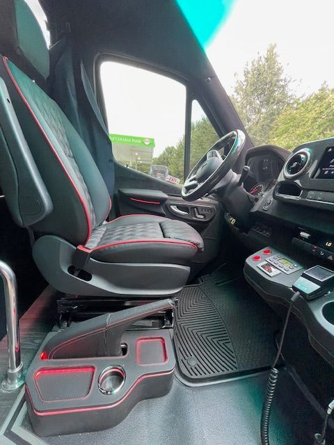 Inside a truck cab with black seats, red accents, and the dashboard and steering wheel visible.
