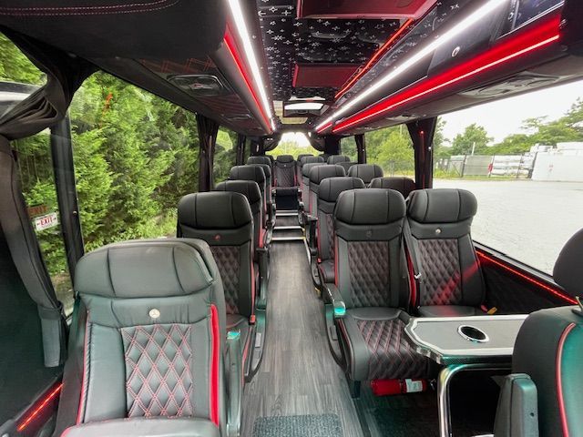 Empty luxury coach interior with black quilted seats, red accents, and overhead LED lighting