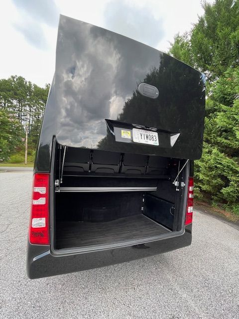 Open rear cargo door of a black van, showing an empty storage compartment.