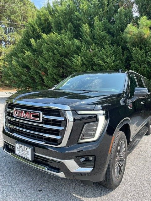 Black GMC pickup truck parked outdoors in front of green trees