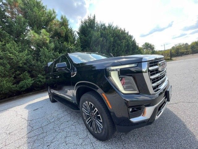 Black GMC SUV parked on a cracked lot beside trees under a cloudy sky