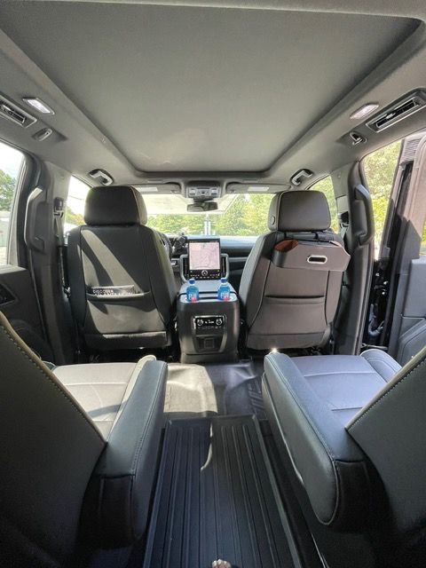 Interior of a minivan with open sliding doors, showing black seats and a center touchscreen display.