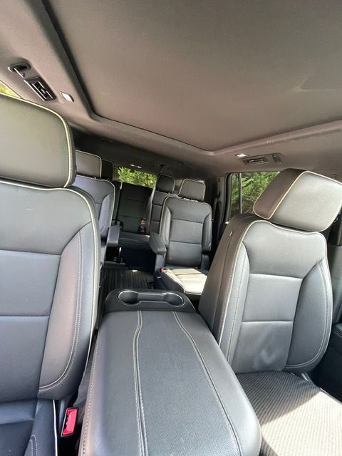 Interior of a gray car SUV with three rows of seats and a sunroof view.