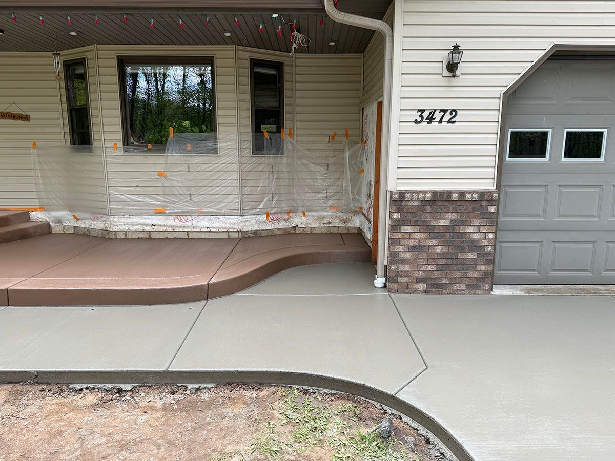 The front of a house with a concrete walkway and a gray garage door
