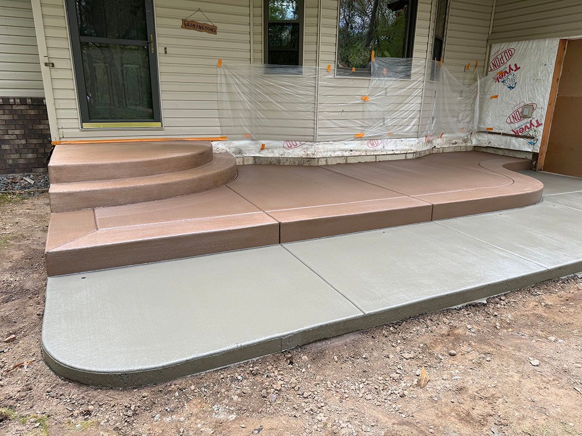 A concrete porch with stairs is being built in front of a house