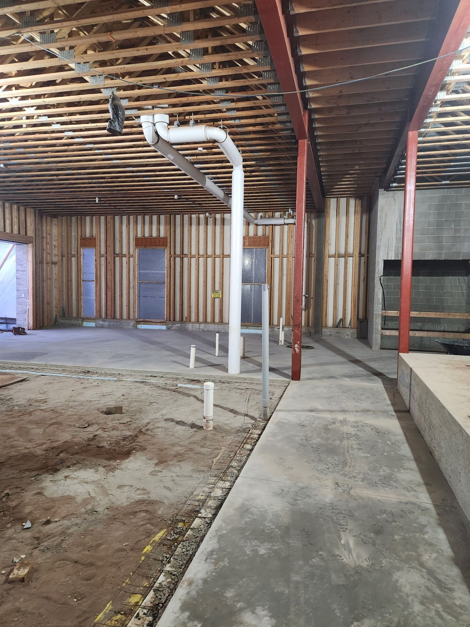 A large empty room with a concrete floor and a wooden ceiling.