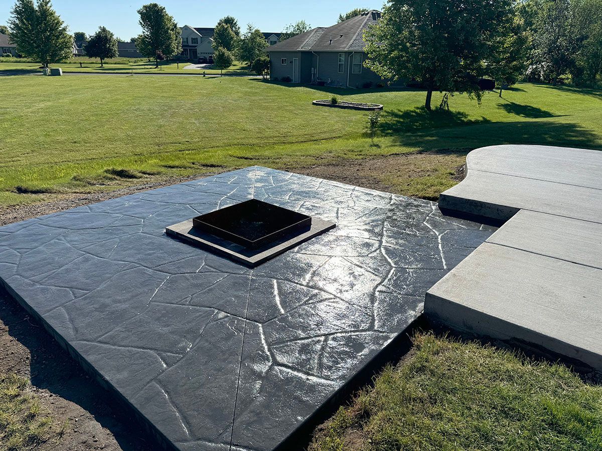 A concrete patio with a fire pit in the middle of it