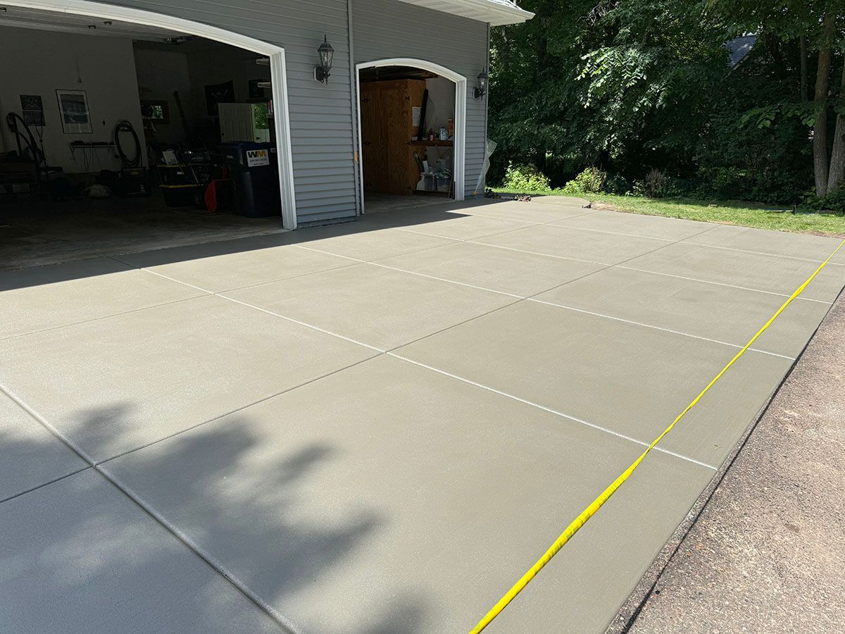 A concrete driveway with a yellow line on it in front of a garage
