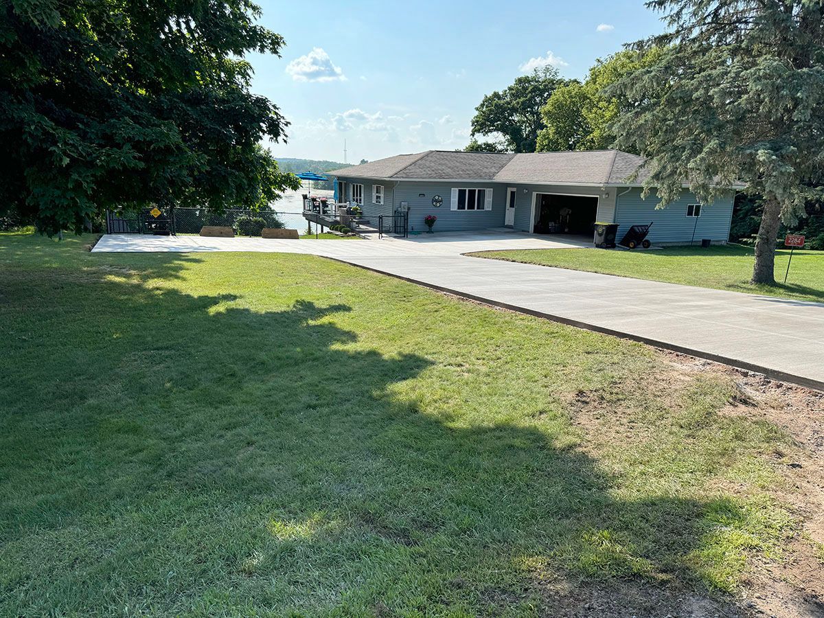 A house with a driveway leading to it and a large lawn in front of it