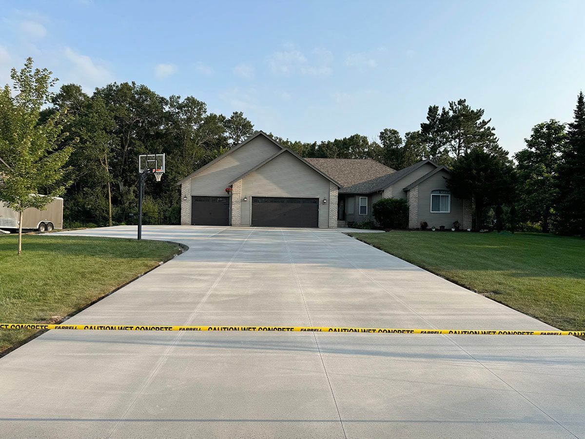 A concrete driveway leading to a house with a basketball hoop