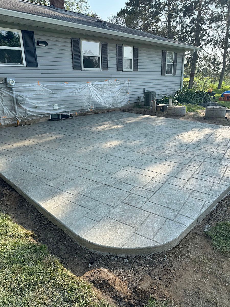 A thick concrete patio is being built in front of a house