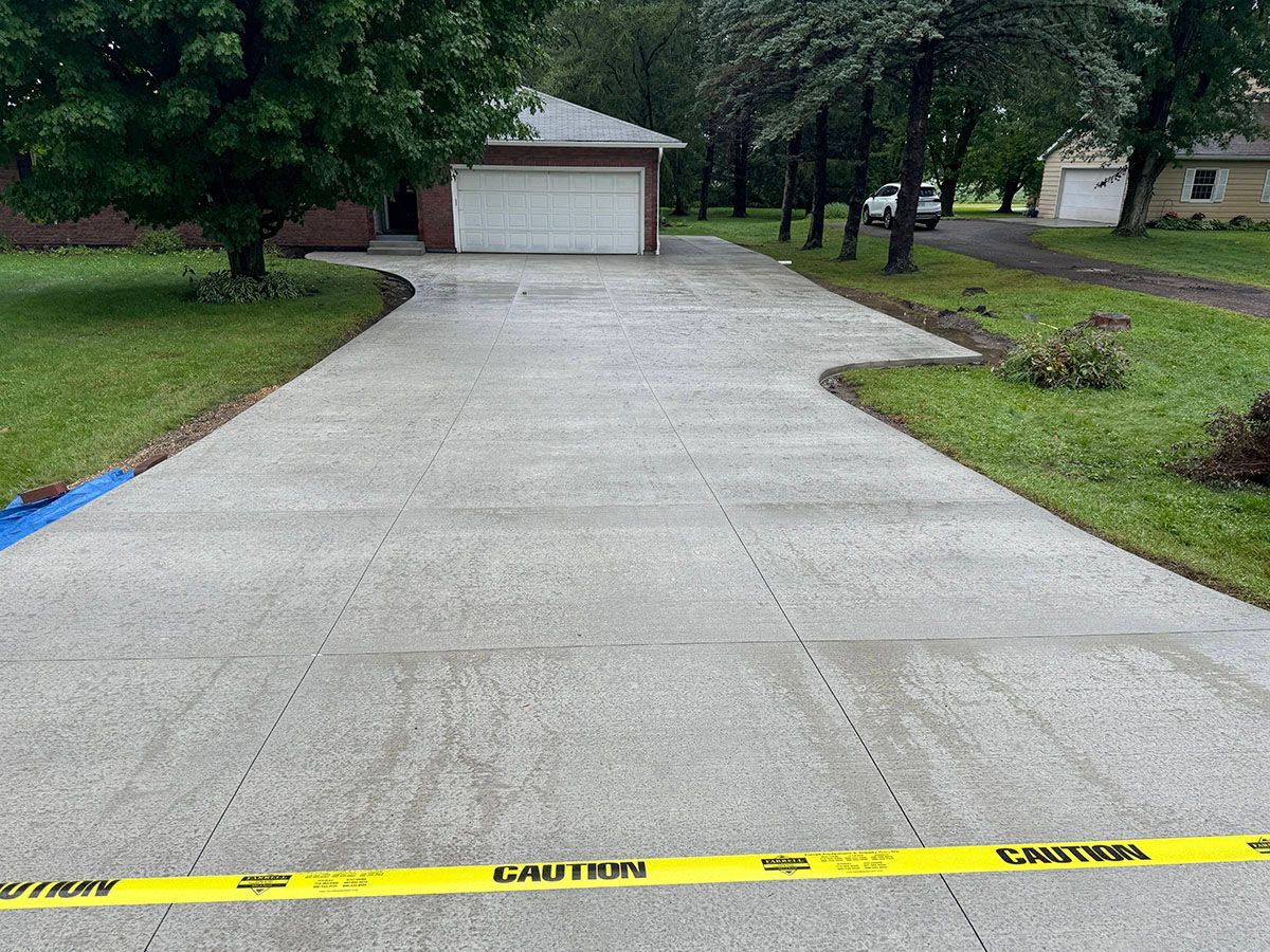 A concrete driveway leading to a garage with a yellow caution tape