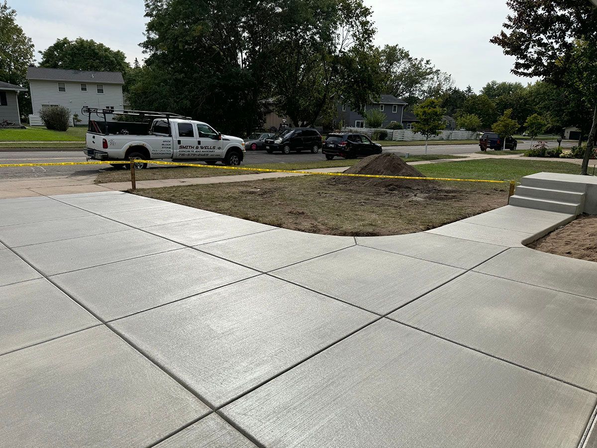 A white truck is parked on the side of a concrete driveway